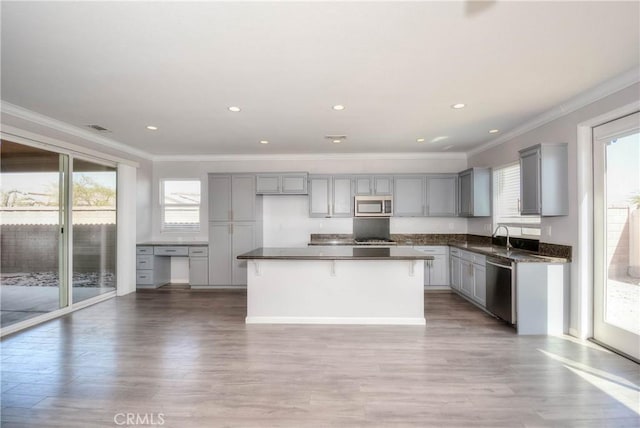 kitchen featuring stainless steel appliances, a sink, plenty of natural light, gray cabinets, and dark countertops