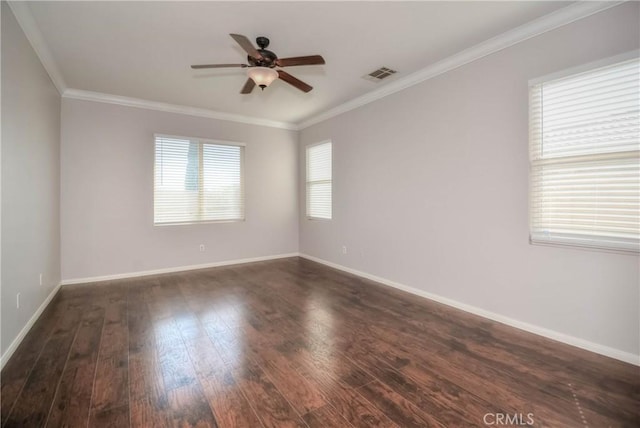 empty room with baseboards, visible vents, a ceiling fan, dark wood finished floors, and crown molding