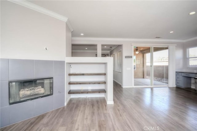 unfurnished living room with wood finished floors, a tile fireplace, and crown molding