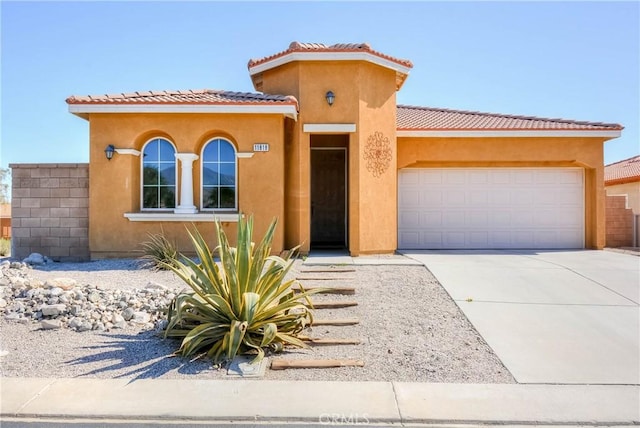 mediterranean / spanish-style home featuring an attached garage, driveway, a tile roof, and stucco siding