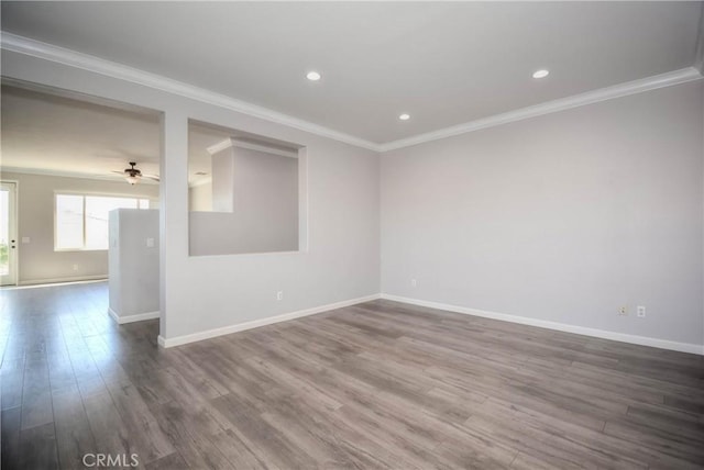 spare room with a ceiling fan, dark wood finished floors, crown molding, and baseboards