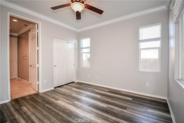 unfurnished bedroom with ornamental molding, a closet, wood finished floors, and baseboards