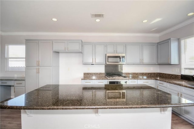 kitchen featuring stainless steel appliances, visible vents, ornamental molding, gray cabinets, and plenty of natural light