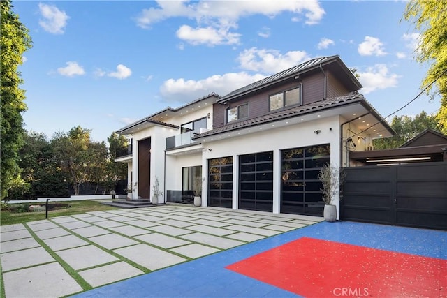 rear view of property featuring a garage, a patio area, a balcony, and stucco siding