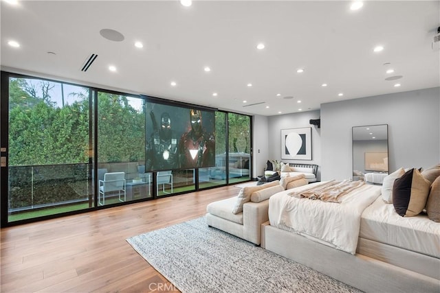 bedroom featuring access to exterior, floor to ceiling windows, multiple windows, and wood finished floors