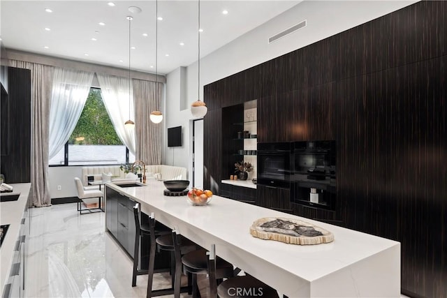 kitchen with a spacious island, a sink, marble finish floor, light countertops, and modern cabinets