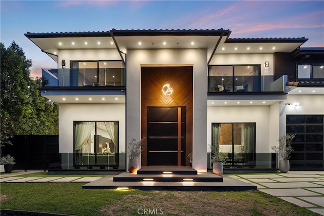 back of property with a balcony and stucco siding