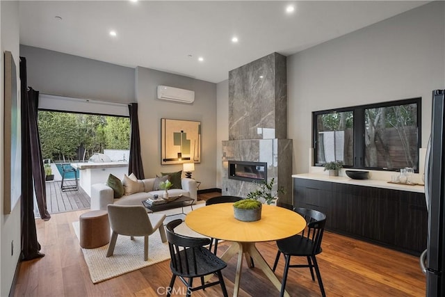 dining space with a wall unit AC, a fireplace, wood finished floors, and recessed lighting