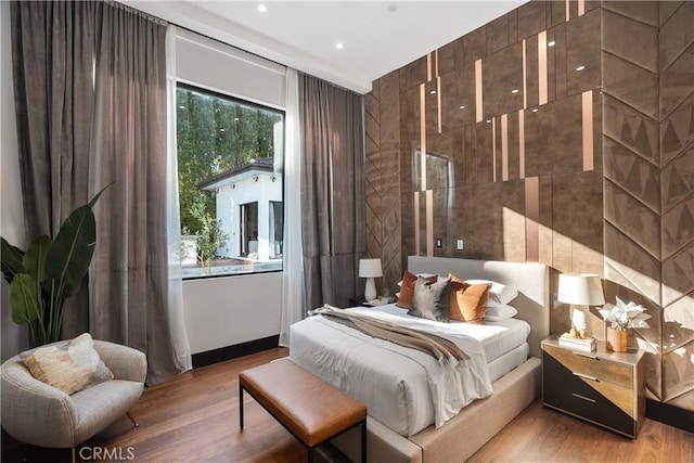 bedroom with wood finished floors, tile walls, and recessed lighting