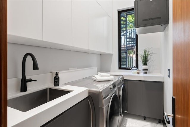 washroom featuring cabinet space, a sink, and washing machine and clothes dryer