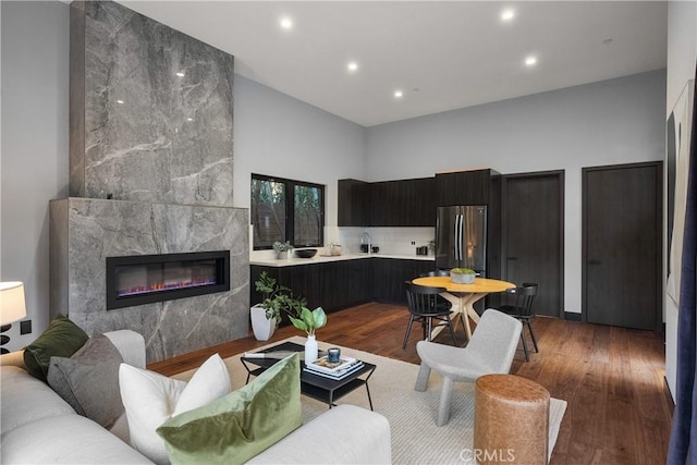 living area with recessed lighting, a fireplace, a high ceiling, and wood finished floors