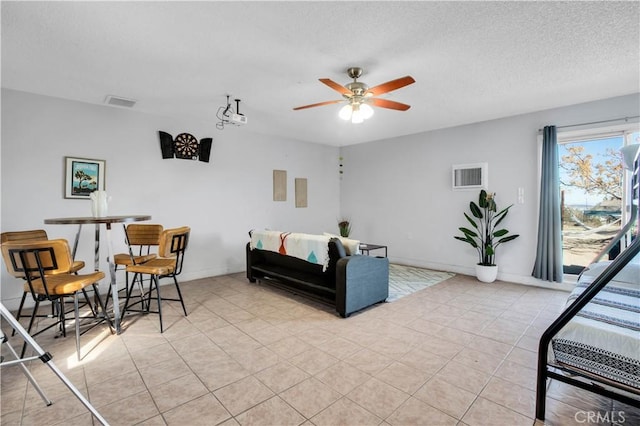 living area with ceiling fan, visible vents, a textured ceiling, and light tile patterned flooring