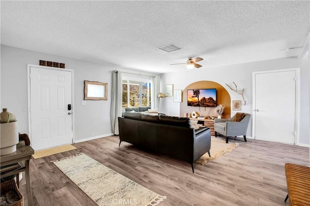 living room with a textured ceiling, wood finished floors, visible vents, and baseboards