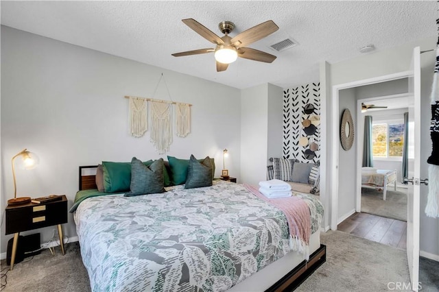 bedroom featuring baseboards, visible vents, ceiling fan, a textured ceiling, and carpet floors