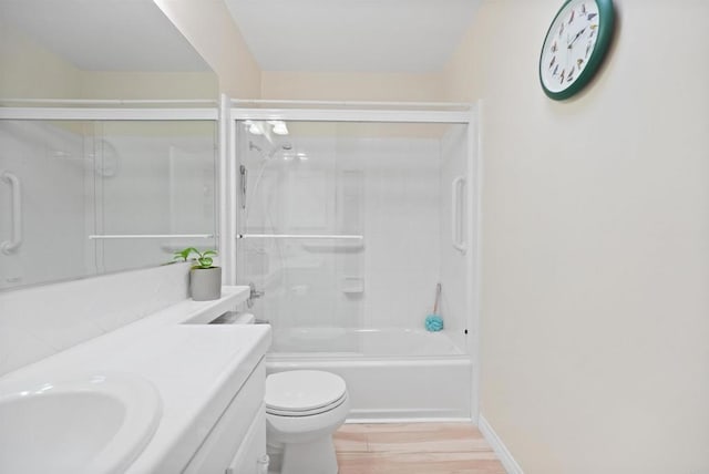 full bath featuring toilet, shower / bath combination with glass door, wood finished floors, vanity, and baseboards