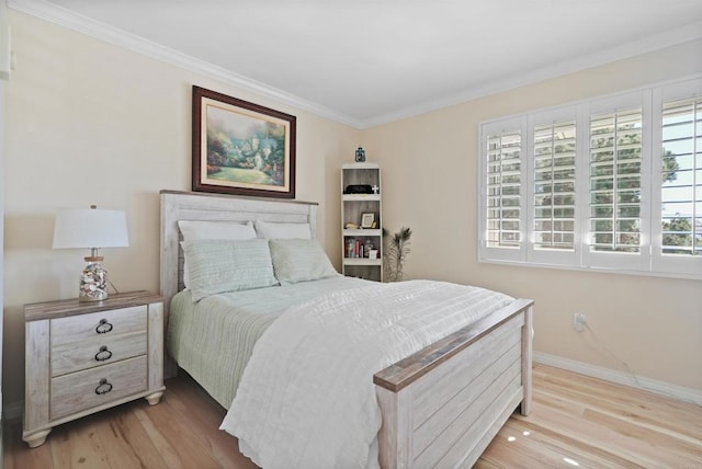 bedroom featuring baseboards, crown molding, and light wood finished floors