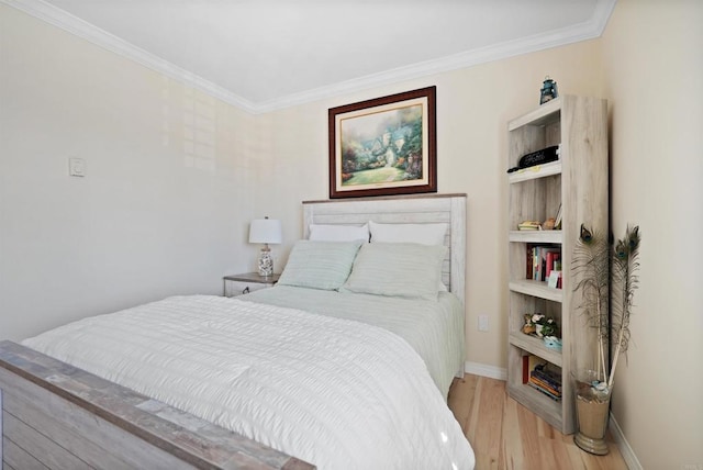 bedroom with baseboards, crown molding, and light wood finished floors