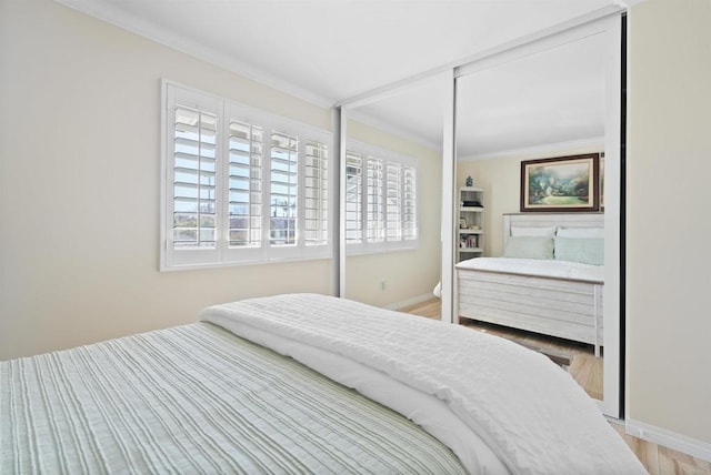 bedroom featuring ornamental molding, wood finished floors, and baseboards