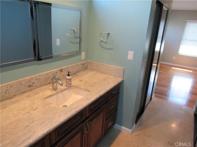 bathroom with wood finished floors, vanity, and baseboards