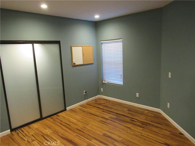 unfurnished bedroom with recessed lighting, wood finished floors, and baseboards