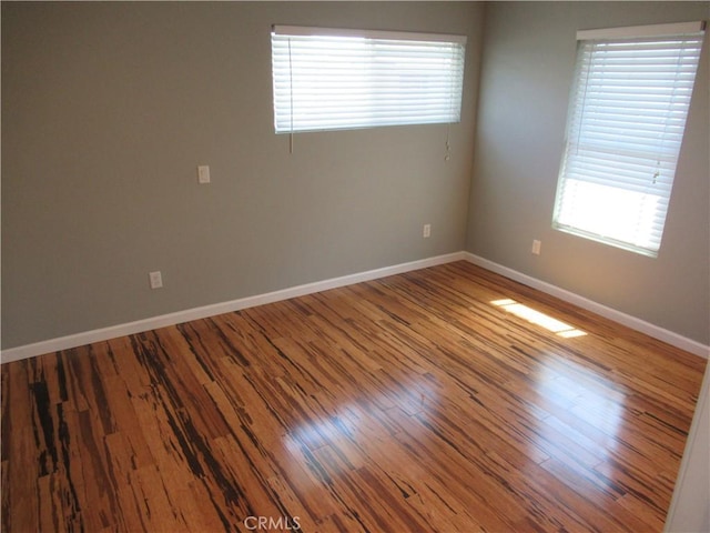 unfurnished room with baseboards and wood finished floors