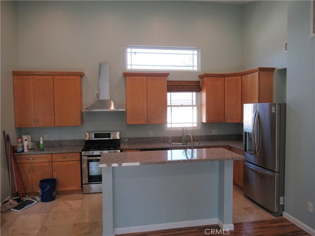 kitchen with stainless steel appliances, a towering ceiling, a sink, an island with sink, and ventilation hood