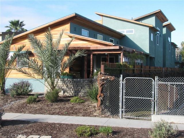 view of front facade with a gate, fence, and stucco siding