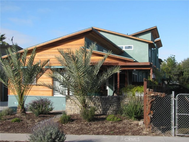 view of property exterior featuring a gate, fence, and stucco siding