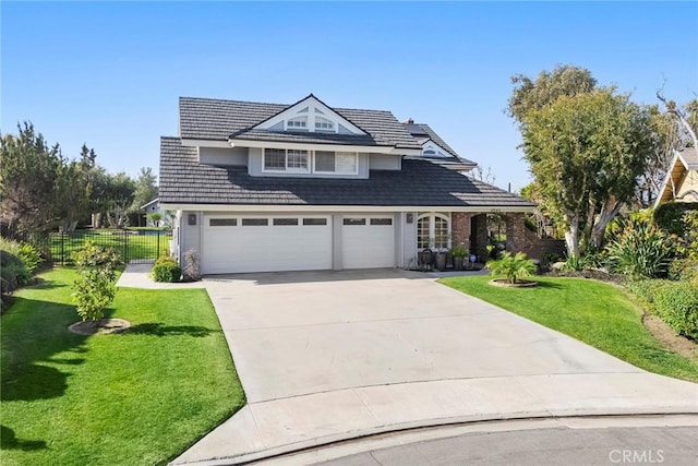 view of front facade featuring driveway, a front lawn, an attached garage, and fence