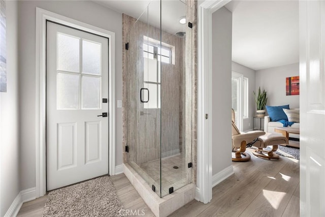 full bathroom with a shower stall, baseboards, and wood finished floors