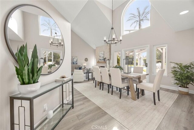 dining area with light wood finished floors, a healthy amount of sunlight, and a notable chandelier