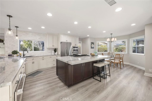 kitchen featuring light wood finished floors, tasteful backsplash, visible vents, and stainless steel appliances