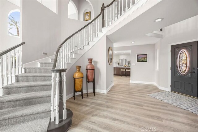 foyer entrance featuring stairs, a high ceiling, baseboards, and wood finished floors