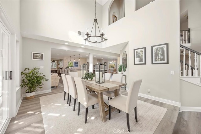 dining room featuring a chandelier, wood finished floors, visible vents, baseboards, and stairway