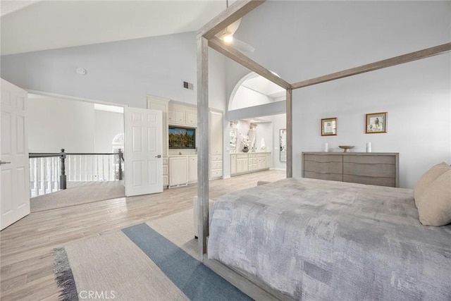 bedroom featuring visible vents, light wood-style flooring, ensuite bath, high vaulted ceiling, and beamed ceiling