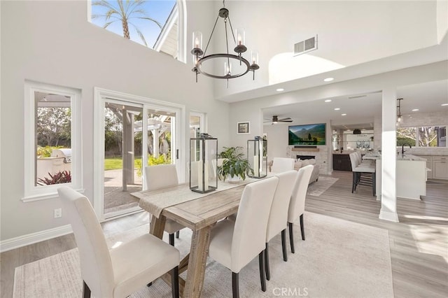 dining room with light wood-style flooring, a fireplace, visible vents, and baseboards