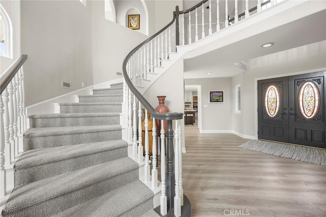 foyer with baseboards, visible vents, a towering ceiling, wood finished floors, and french doors