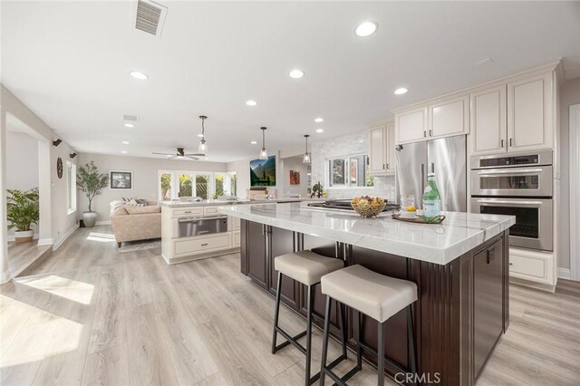 kitchen with recessed lighting, a spacious island, visible vents, open floor plan, and appliances with stainless steel finishes