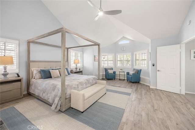 bedroom with high vaulted ceiling, light wood-style flooring, and baseboards