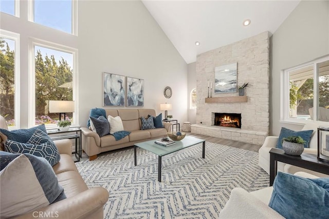 living area featuring high vaulted ceiling, recessed lighting, a stone fireplace, and wood finished floors