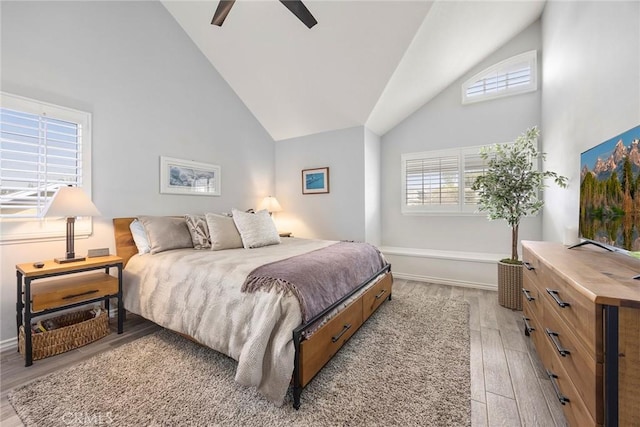 bedroom featuring high vaulted ceiling, light wood finished floors, multiple windows, and a ceiling fan