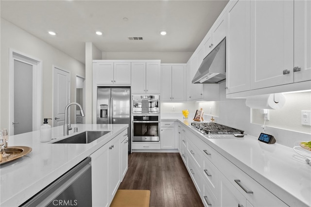 kitchen with white cabinets, appliances with stainless steel finishes, light countertops, under cabinet range hood, and a sink