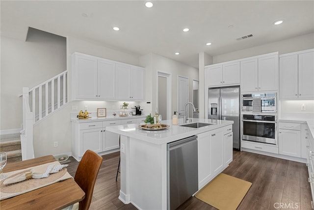 kitchen featuring appliances with stainless steel finishes, visible vents, dark wood-style flooring, and a sink