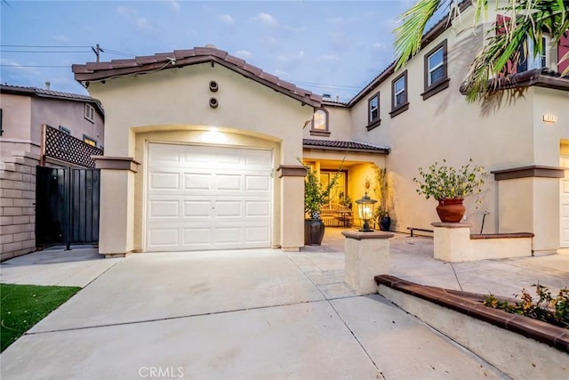 mediterranean / spanish home featuring a garage, driveway, a tiled roof, and stucco siding