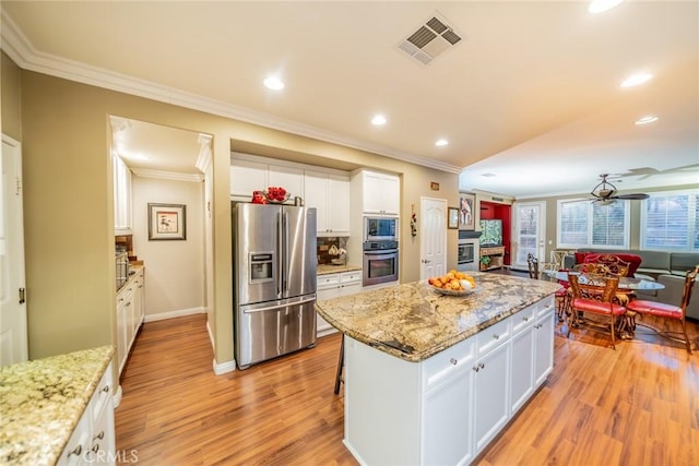 kitchen featuring visible vents, white cabinetry, appliances with stainless steel finishes, ornamental molding, and light wood finished floors