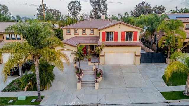 mediterranean / spanish-style house with a garage, a tiled roof, concrete driveway, and stucco siding