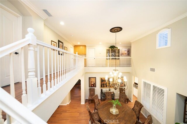 dining space featuring crown molding, wood finished floors, visible vents, and an inviting chandelier