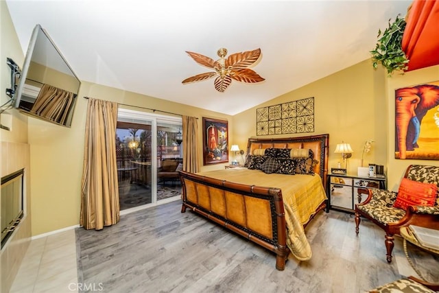 bedroom featuring ceiling fan, access to outside, vaulted ceiling, and wood finished floors