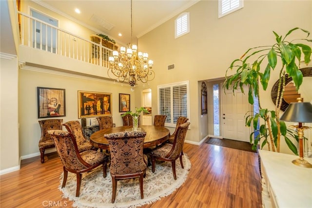 dining space with visible vents, baseboards, wood finished floors, an inviting chandelier, and crown molding