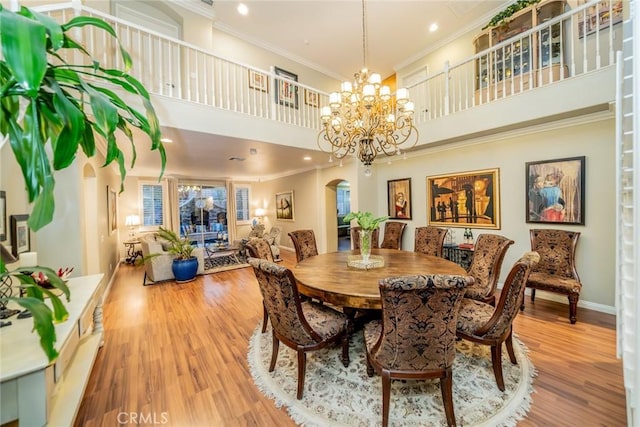 dining area featuring arched walkways, wood finished floors, baseboards, ornamental molding, and an inviting chandelier